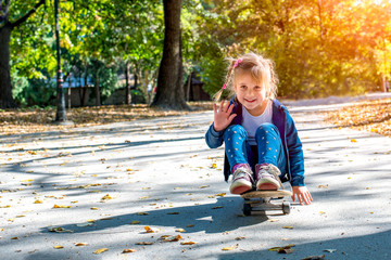 Adorable little girl enjoying the day while riding skateboard in the park