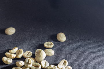 Fototapeta na wymiar Close-up of green unroasted coffee beans on a black background