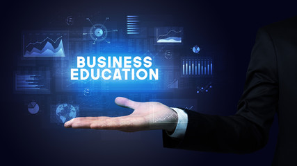 Hand of Businessman holding BUSINESS EDUCATION inscription, business success concept