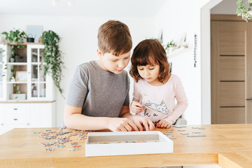 Brother and sister playing puzzles at home. Stay at home activity for kids.