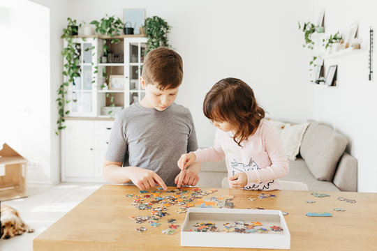 Brother and sister playing puzzles at home. Stay at home activity for kids.