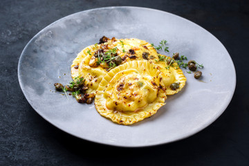Traditionelle italienische Ravioli Pasta angeboten mit Kapern und Zwiebel Chili Pesto als closeup auf einem Modern Design Teller