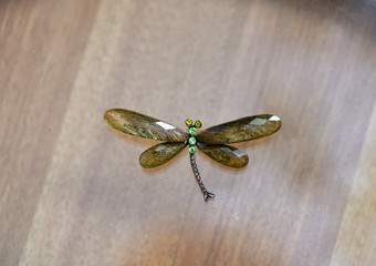 green glass dragonfly on a brown background