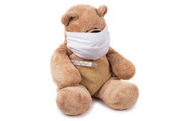 The teddy bear sits ill with a coronavirus in a medical mask