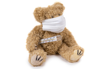 The teddy bear sits ill with a coronavirus in a medical mask