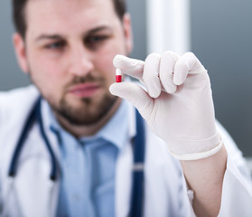 Man doctor woth tablet capsule in hands with gloves