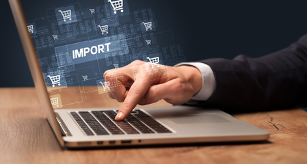 Obraz na płótnie Canvas Businessman working on laptop with IMPORT inscription, online shopping concept