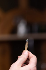 Smoking joint rolled from brown paper in male hand close up