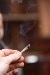 Smoking joint rolled from brown paper in male hand close up