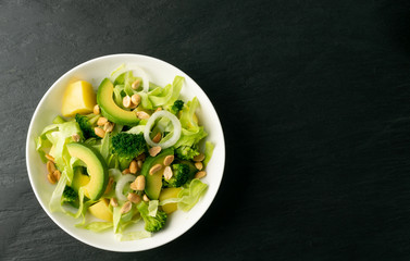 Green Salad with Avocado, Cucumber and Nuts on White Plate