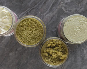 The natural ingredients green body scrab and creams  in the jars on gray stone background. Skin care, spa and clean cosmetic concept. Health and beauty. Cosmetic with matcha and kale. Sea salt