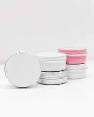 Set of silver, pink and white metal jars containers on white background. Container for tea, spices, cosmetic or food. Colorful. Cream packing, cans