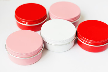 Set of red, pink and white metal jars containers on light background. Container for tea, spices, cosmetic or food. Colorful. Cream packing