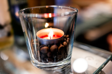 Macro closeup of small tea red candle light on glass table in cup cafe restaurant romantic...