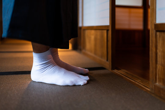 Traditional japanese house or ryokan with man in kimono closeup of legs feet with tabi white socks by shoji sliding paper doors and tatami mat floor