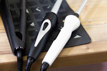Black and white curling iron, black hair straightener. Hairdresser tools for creating hairstyles....