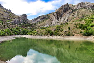 Fototapeta na wymiar A small lake with crystal clear water among the majestic mountains