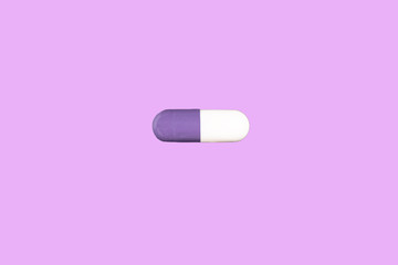 Two-tone medical capsule isolated on a pink background.