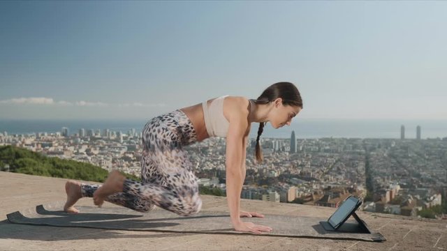 Athletic woman watching video on tablet during yoga training outdoors