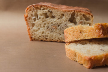 Homemade rye-wheat yeast-free bread with live sourdough. Two slices of rye-wheat bread close-up on a beige linen cloth with the remaining loaf of bread in the background with soft focus