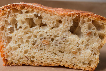 Homemade rye-wheat yeast-free bread with live sourdough. A loaf of rye-wheat bread with flax and sunflower seeds in a close-up section on a beige linen fabric