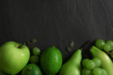 Flat lay top view. Summer abstract creative trendy fresh concept. Green fruits background. Dark stone slake plate with copy space.