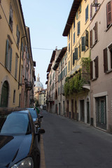 Fototapeta na wymiar Narrow street with Saint Mary of the Peace Church on background, Brescia Old Town, Lombardy, Italy.