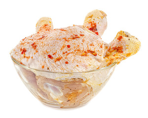 Marinated with spices chicken thigh and chicken drumsticks in transparent glass bowl isolated on...