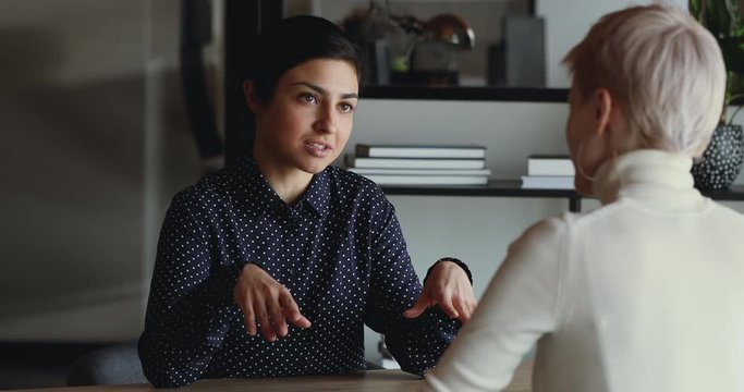 Confident indian female job applicant speaks to hr at job interview. Young business woman professional insurer consulting client about insurance at office meeting. Staffing agency negotiations concept