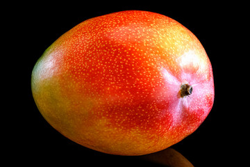 Fresh ripe mango fruit isolated on black background with reflection on glossy surface