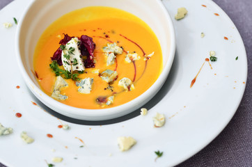 food pumpkin soup with spices and seeds in a white plate