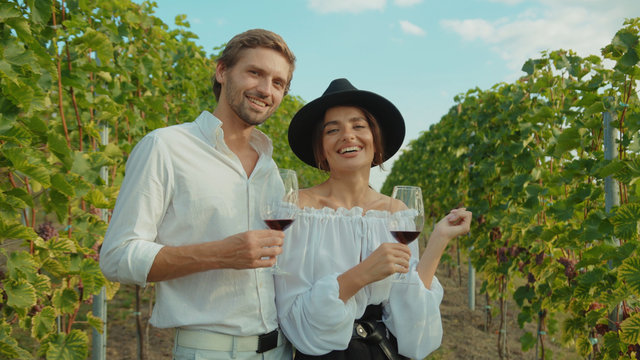 Gorgeous happy couple of married man and woman enjoying wine tasting exploring beautiful vineyard valley together on honeymoon. - Powered by Adobe
