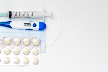 Obraz premium Facial protective mask, syringe, thermometer and pills. Flat lay and copy space concept. Pharmacy theme.