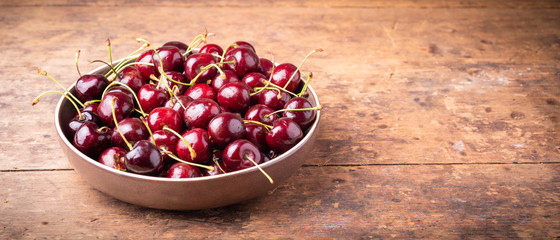 Ripe cherries on a wooden table - panoramic background with copy space