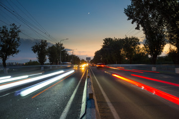Long Exposure moving cars at sunset, with trees and blue sky.