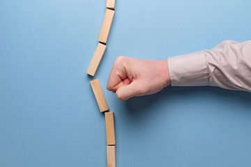 The concept of breaking stereotypes. Hand holds wooden blocks on a blue background. - obrazy, fototapety, plakaty
