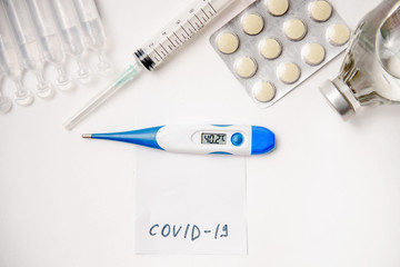 Pills, thermometer and syringes on white background. Coronavirus (COVID-19) epidemic. Flat lay, top view, copy space.
