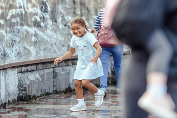 Happy beautiful girl running through the spray of water.