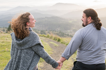 A happy young expecting couple enjoy their social connection and time together in an outdoor setting in the mountains.