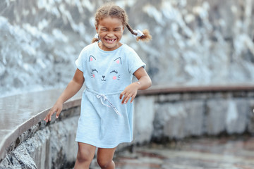 Happy beautiful girl running through the spray of water. © lialia699