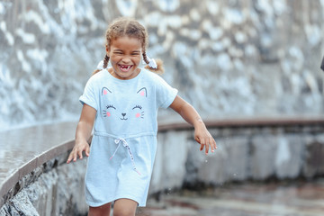 Naklejka premium Happy beautiful girl running through the spray of water.