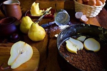 Kitchen table with baking goods on the surface.  Baking tin being lined with pears for an upside...