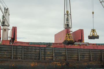 Loading coal from cargo barges onto a bulk vessel using ship cranes  in offshore coal cargo terminal.

