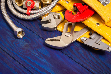 Plumbing tools in the yellow bag and spare parts on blue wooden boards are used to replace or repair