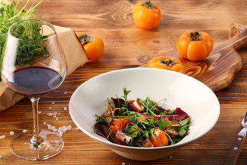 persimmon with meat and persimmon and red wine on wooden table. microgreen and ingredients
