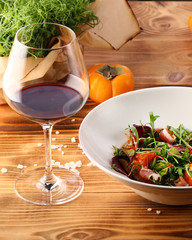 persimmon with meat and persimmon and red wine on wooden table. microgreen and ingredients