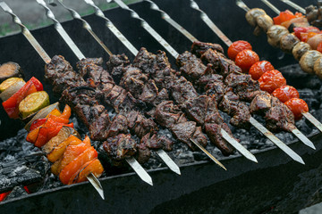 Meat skewered and vegetables grill. Hot tasty kebab, pepper and tomatoes vith smoke.