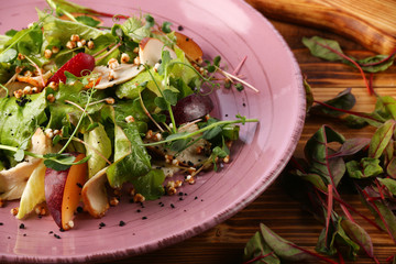 plum salad with herm microgreen and pine nuts in plate on wooden table.