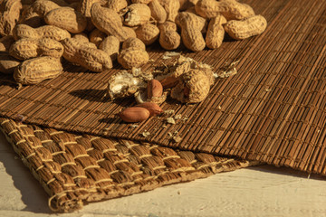a scattering of peeled and unshelled peanuts on mats and a white wooden table
