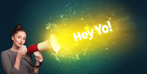 Young woman yelling to loudspeaker with Hey Yo! inscription, modern media concept